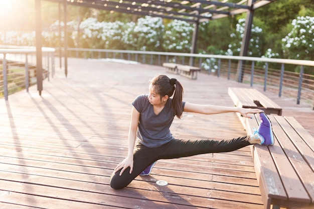 Flexible Frau, die sich mit dem Bein auf einer Bank