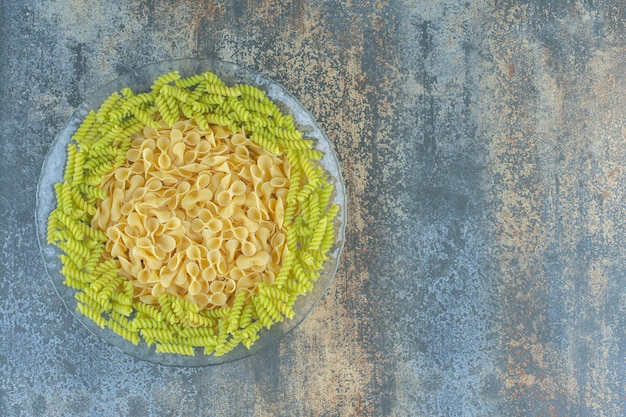 Fliege und Fusilli-Nudeln in der Schüssel auf der Marmoroberfläche.