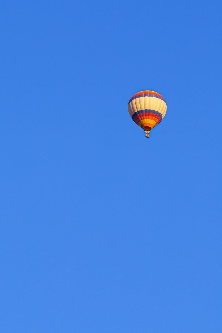 Kostenlose Foto fliegender mehrfarbiger ballon im strahlend blauen himmel