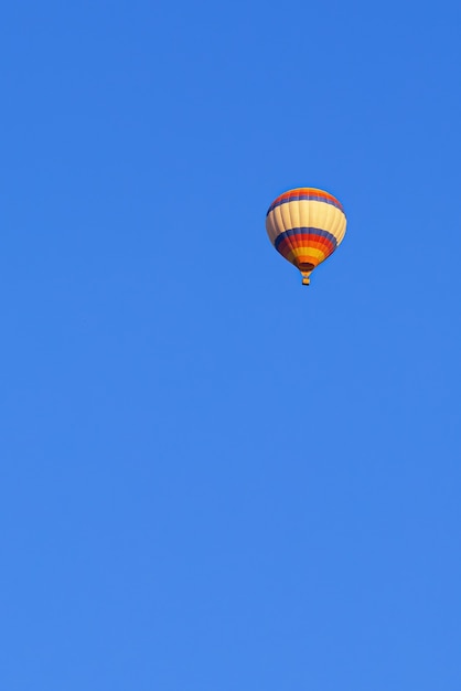 Fliegender mehrfarbiger Ballon im strahlend blauen Himmel