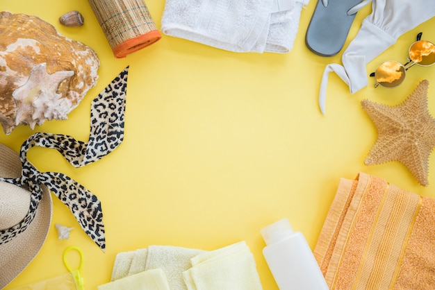 Flip Flop in der Nähe von Handtuch mit Seestern und Badeanzug mit Sonnenbrille zwischen Hut und Muschel