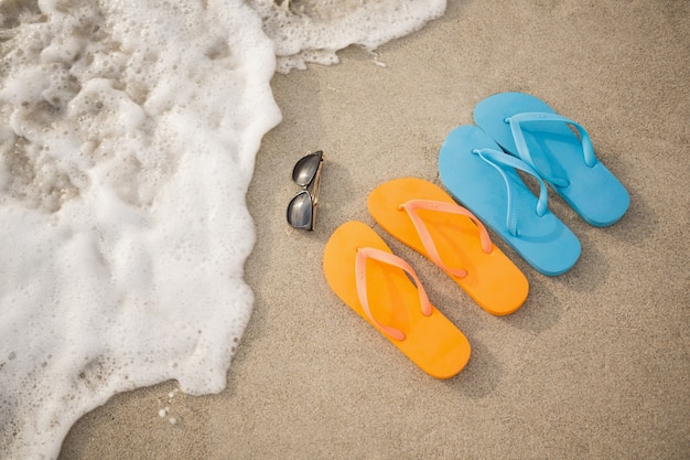 Flip-Flops, Sonnenbrille und Seestern in Sand