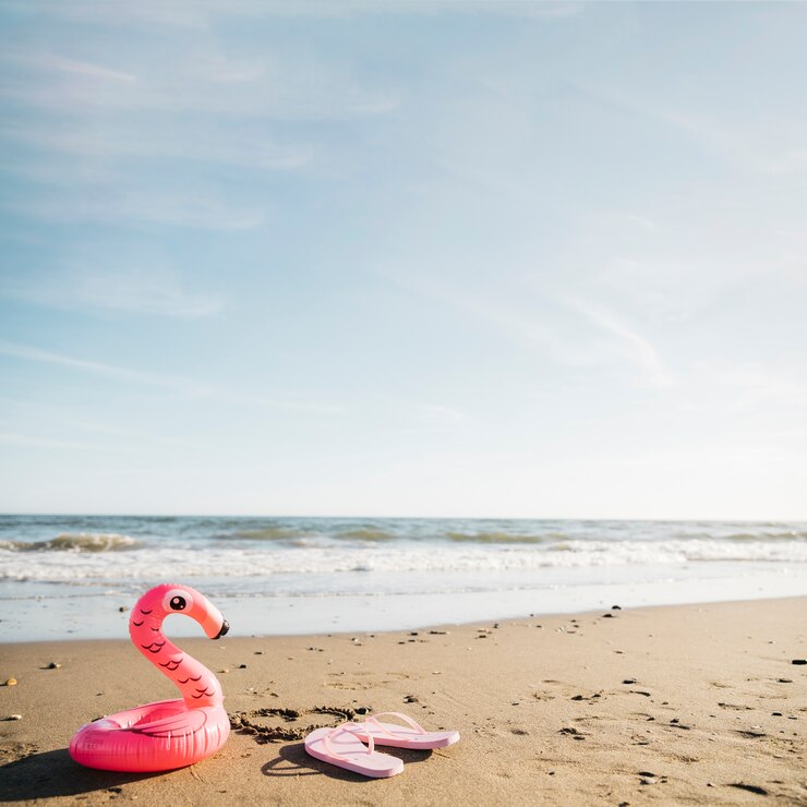 Kostenlose Foto flip-flops und aufblasbarer flamingo am strand
