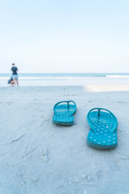 Kostenloses Foto flipflops auf einem sandigen ozeanstrand