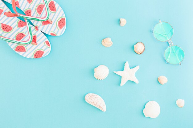 Flipflops Sonnenbrillen und Muscheln auf hellem Hintergrund