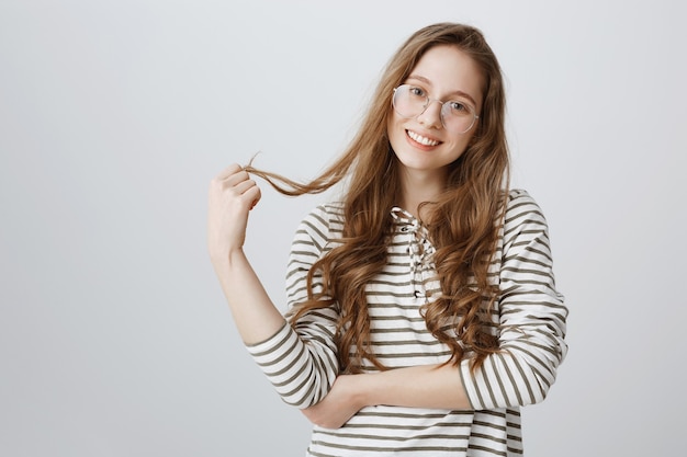 Flirty Mädchen in Brille, mit kokettem Haar spielend