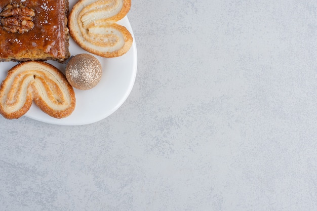 Flockige kekse und ein bakhlava auf einer platte mit einer kugel auf marmoroberfläche