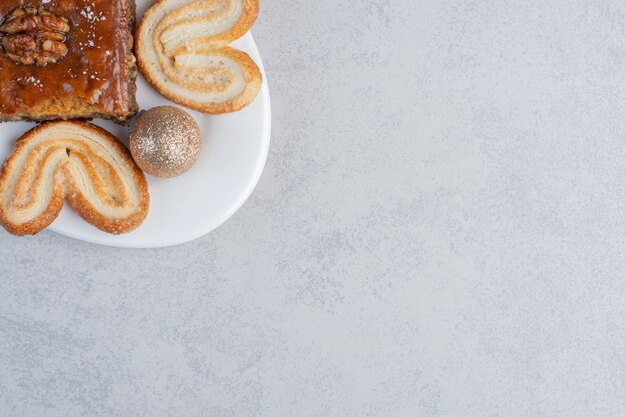 Flockige Kekse und ein Bakhlava auf einer Platte mit einer Kugel auf Marmoroberfläche