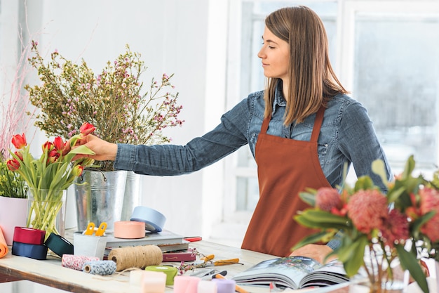 Florist bei der Arbeit: Das junge Mädchen macht einen modernen Blumenstrauß aus verschiedenen Blumen