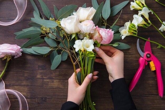 Florist bei der Arbeit Frau, die Mode modernen Blumenstrauß von verschiedenen Blumen auf Holzoberfläche macht