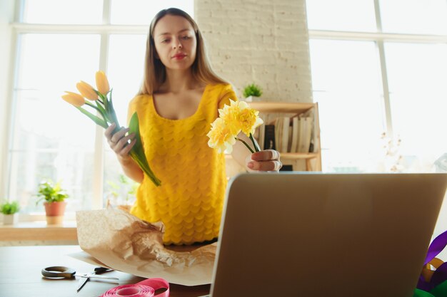 Florist bei der Arbeit: Frau zeigt, wie man Blumenstrauß mit Tulpen macht.