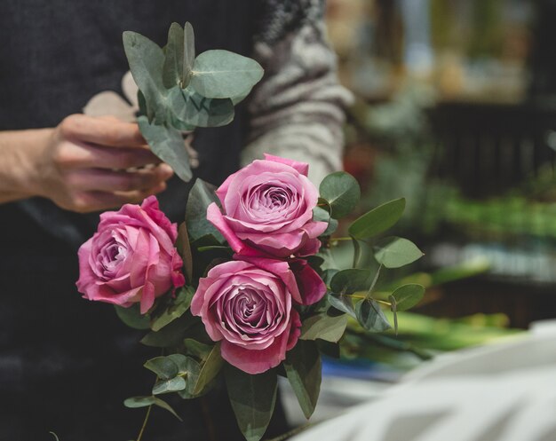 Florist, der einen Blumenstrauß von den rosa Rosen macht