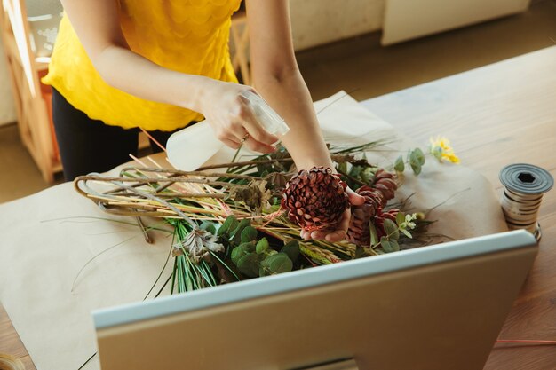 Kostenloses Foto floristin bei der arbeit frau zeigt, wie man blumenstrauß zu hause arbeitet, hautnah