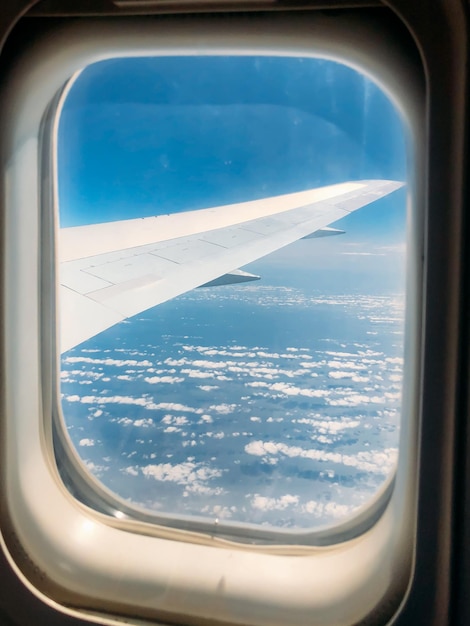 Flügel durch das Fenster des Flugzeugs im atemberaubenden Himmel bei Sonnenuntergang