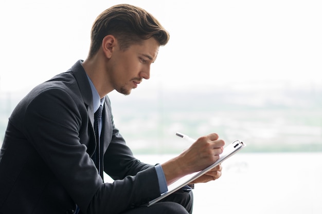 Focused Adult Geschäftsmann-Schreiben auf Zwischenablage