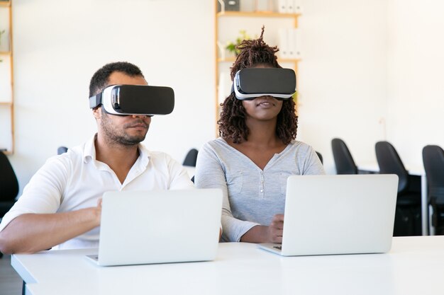 Fokussierte Afroamerikanertester, die VR-Gläser im Büro tragen