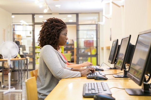 fokussierte Frau, die auf Computertastatur schreibt