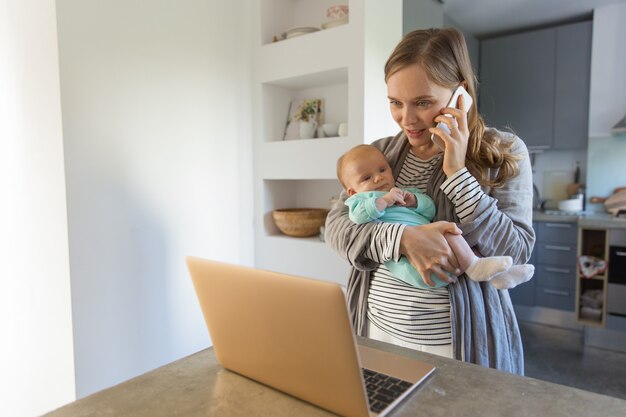 Fokussierte junge Mutter, die Baby hält