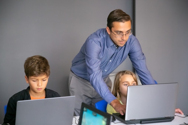 Fokussierte lehrerin hilft mädchen bei der aufgabe und tippt auf der tastatur