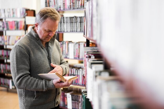 Fokussierter älterer Mann, der Buch betrachtet