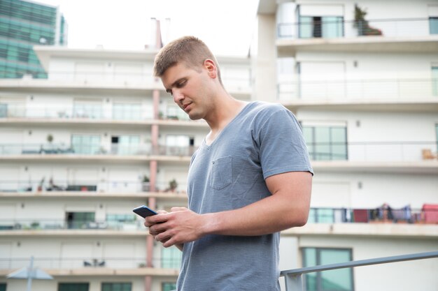 Fokussierter junger Mann, der Smartphone verwendet