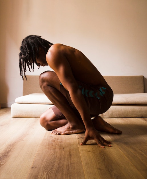Kostenloses Foto fokussierter mann, der seitlich sitzt und zuhause meditiert