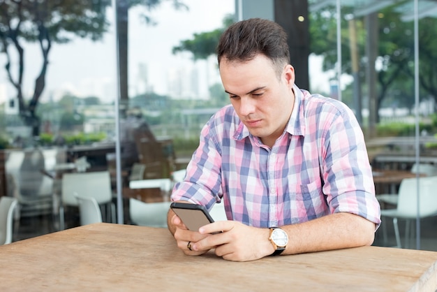 Fokussierter Mann, der Smartphone Café im im Freien verwendet