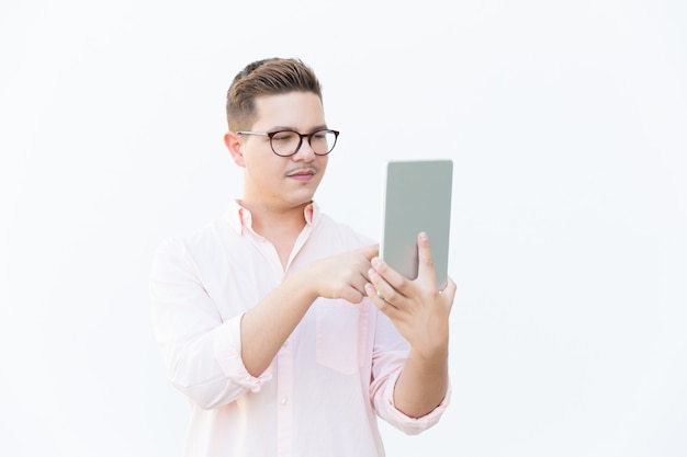 Fokussierter nerdy Kerl in den Brillen unter Verwendung der Tablette