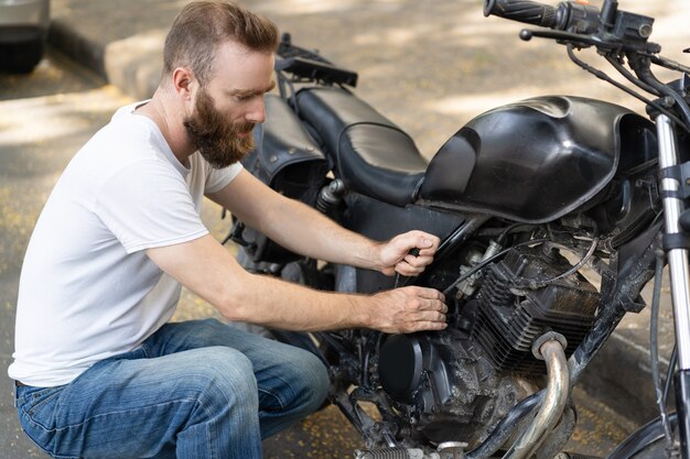 Fokussierter Reiter, der versucht, gebrochenes Motorrad wiederzubeleben