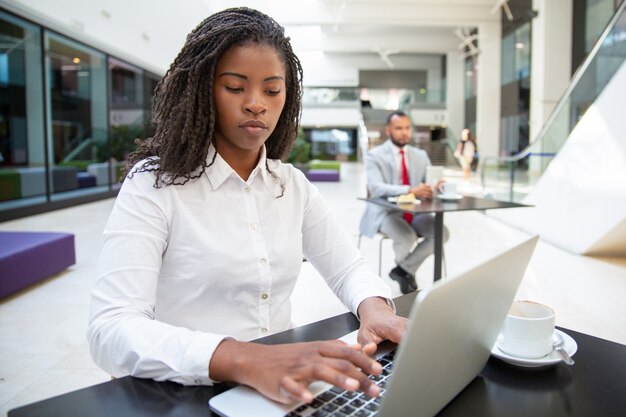 Fokussierter weiblicher Manager, der an Laptop arbeitet