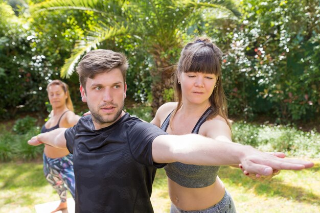 Fokussierter Yogalehrer, der newby hilft