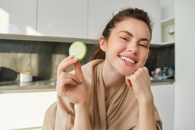 Food- und Lifestyle-Konzept schöne Frau kocht in der Küche, hält rohe Zucchini in der Hand und lächelt