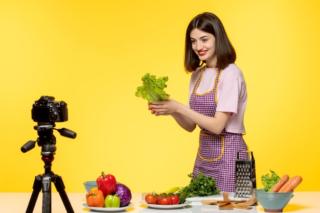 Foodblogger, süßer, reizender Koch in rosa Schürze, der ein Video für soziale Medien aufnimmt, das einen Salat zeigt