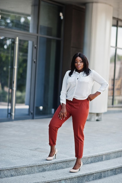 Formal gekleidete afroamerikanische Geschäftsfrau in weißer Bluse und roter Hose Erfolgreiche dunkelhäutige Geschäftsfrau