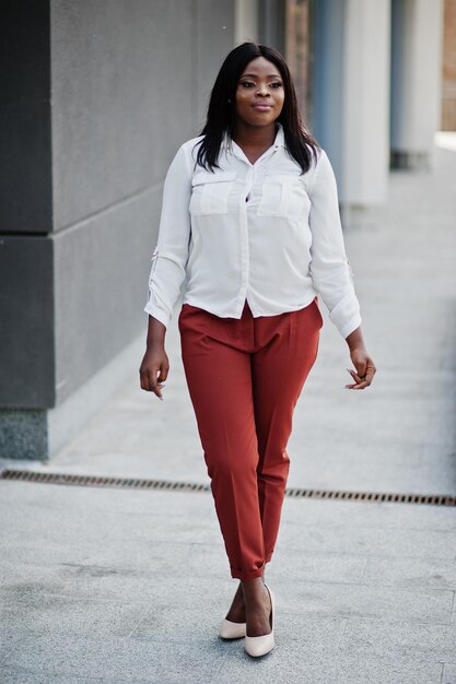 Formal gekleidete afroamerikanische Geschäftsfrau in weißer Bluse und roter Hose Erfolgreiche dunkelhäutige Geschäftsfrau