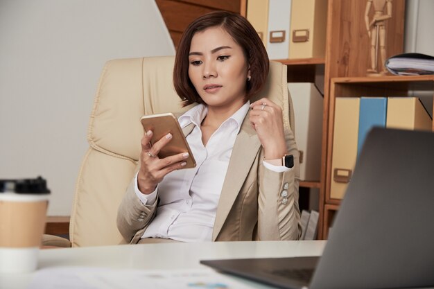 Formale Geschäftsfrau, die Telefon im Büro verwendet