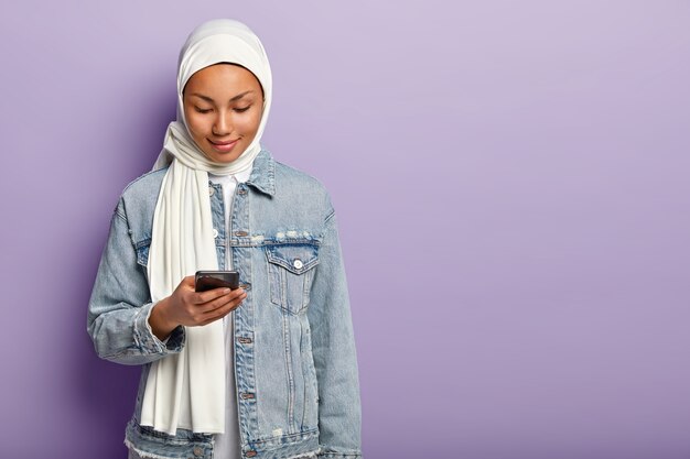 Foto der bezaubernden muslimischen Dame konzentriert in modernem Smartphone-Gerät