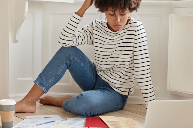 Foto der dunkelhäutigen frau prüft papiergrafiken während des entfernten jobs, plant budgeteinkommen