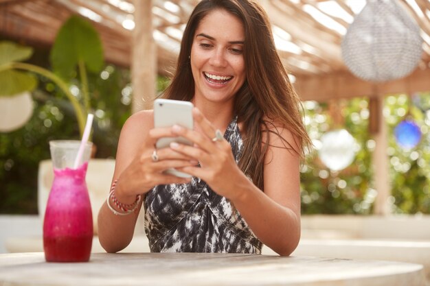 Foto der freudigen Dame mit attraktivem Blick hält modernes Smartphone
