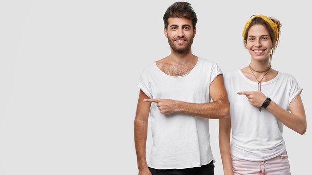 Foto der glücklichen entzückten Frau und des Mannes, die lässig gekleidet sind, zeigen auf die rechte Seite, zeigen freien Platz für Ihre Werbung oder Werbung