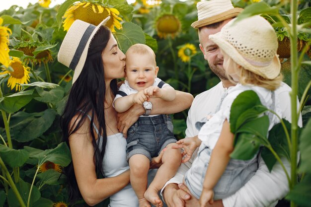 Foto der glücklichen Familie. Eltern und Tochter. Familie zusammen im Sonnenblumenfeld. Mann in einem weißen Hemd.