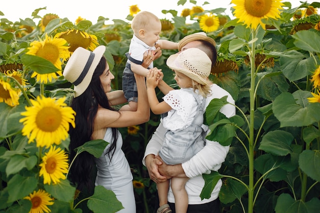 Foto der glücklichen Familie. Eltern und Tochter. Familie zusammen im Sonnenblumenfeld. Mann in einem weißen Hemd.