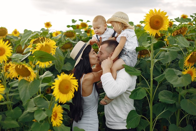 Foto der glücklichen Familie. Eltern und Tochter. Familie zusammen im Sonnenblumenfeld. Mann in einem weißen Hemd.