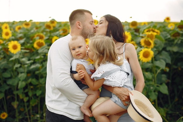 Kostenloses Foto foto der glücklichen familie. eltern und tochter. familie zusammen im sonnenblumenfeld. mann in einem weißen hemd.