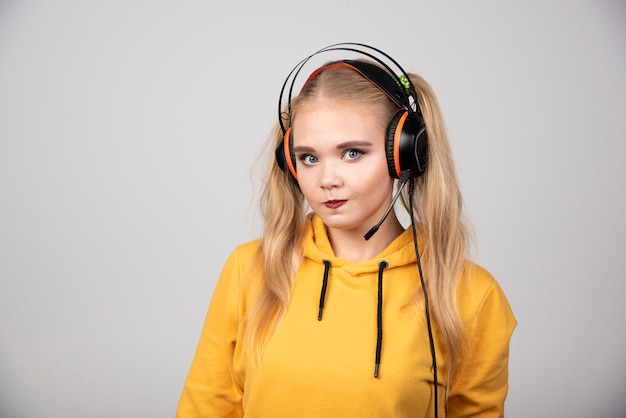 Foto der jungen Frau, die Musik mit Kopfhörern aufwirft und hört.