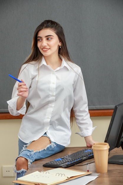 Foto der jungen Geschäftsfrau zeigt ihren Stift beiseite und lächelt