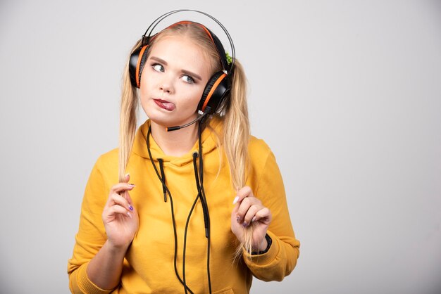 Foto der optimistischen jungen Frau, die Musik mit Kopfhörern aufwirft und hört.