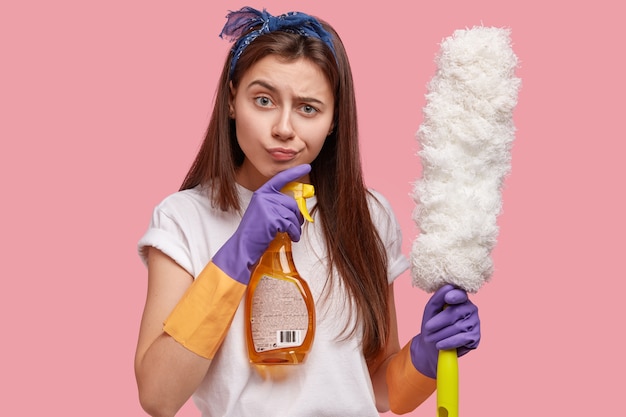 Foto des attraktiven Zimmerservice-Hausmädchens hält Reinigungsausrüstung, schaut mit frustriertem Ausdruck direkt
