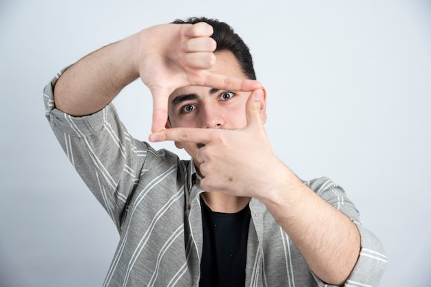 Kostenloses Foto foto des jungen mannes in der freizeitkleidung, die zur kamera über weißer wand aufwirft.