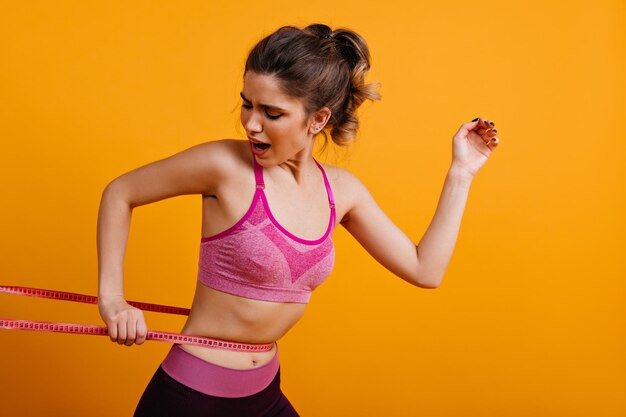 Foto einer besorgten Dame in guter Verfassung Attraktives Mädchen, das nach dem Training Maßband verwendet